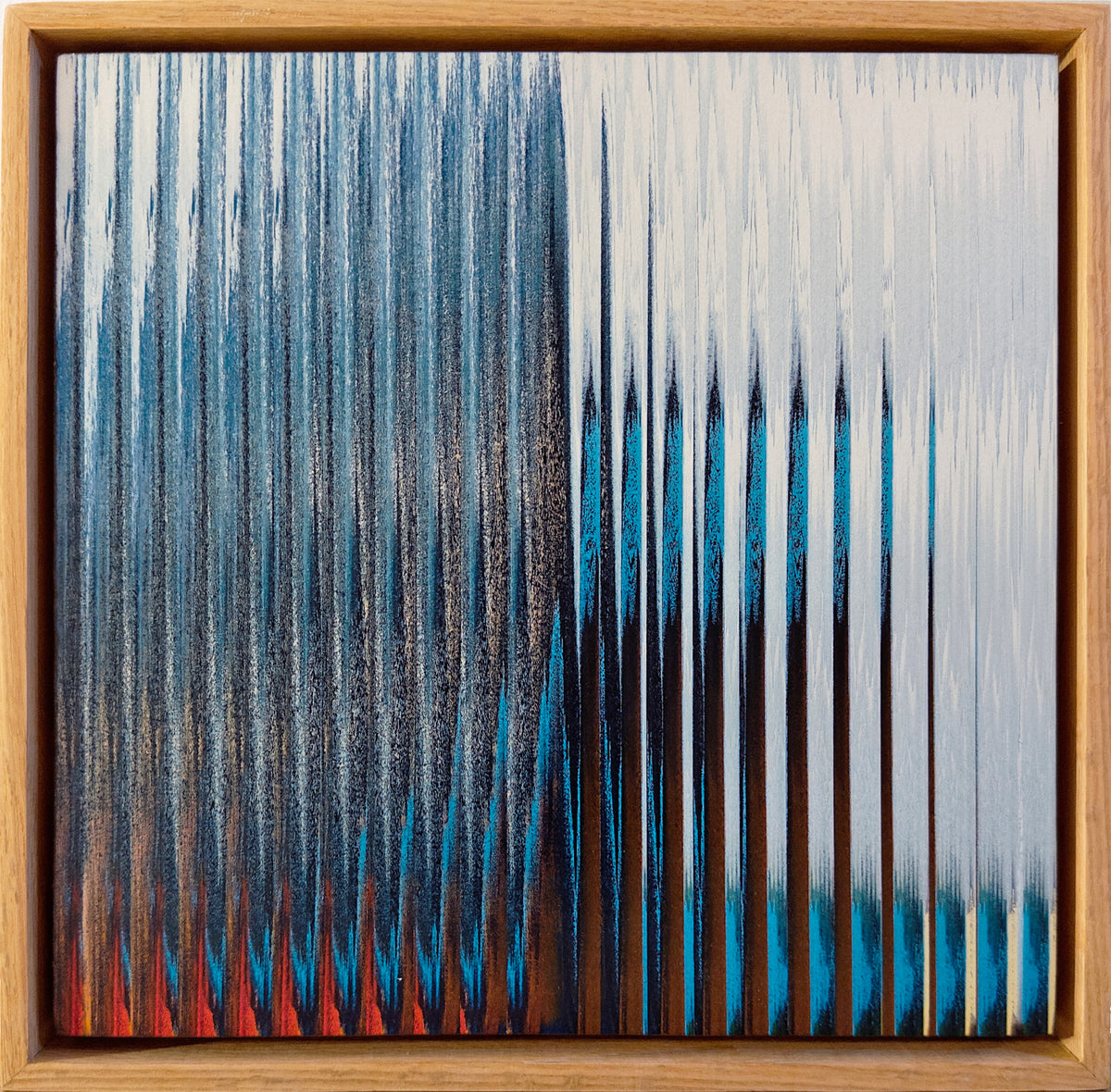 A framed abstract artwork featuring vertical textured brushstrokes in blue, black, white, and red, enclosed in a natural wood frame.
